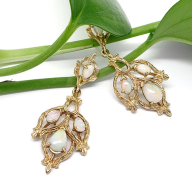 Vintage opal twig earrings in 14kt yellow gold displayed on green plant stems