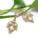 Vintage opal twig earrings in 14kt yellow gold displayed on green plant stems