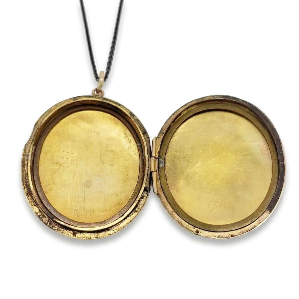 Open vintage gold-filled locket revealing inner oval compartments