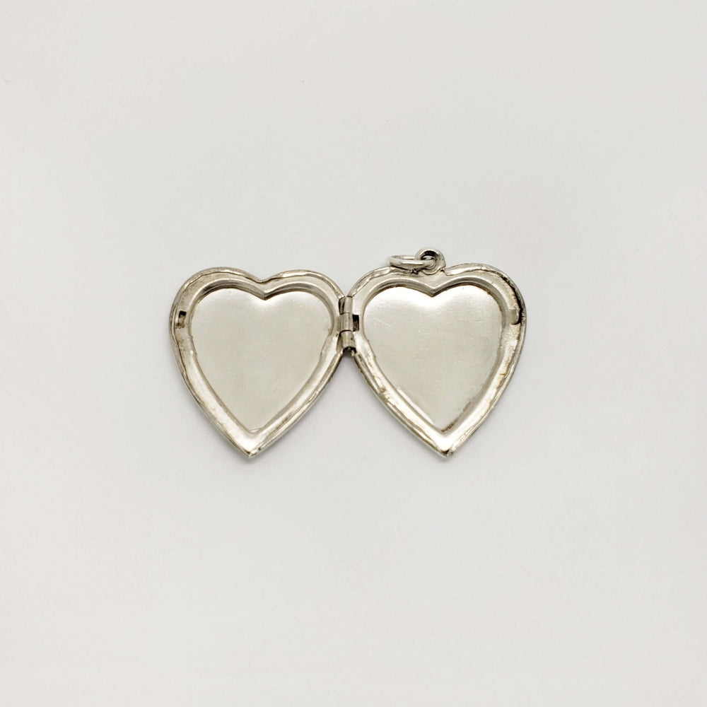 Open vintage sterling silver heart locket with empty photo compartments