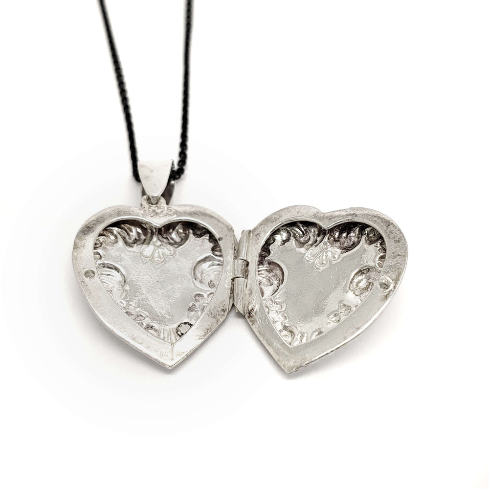 Open vintage sterling silver heart locket showing detailed interior engraving