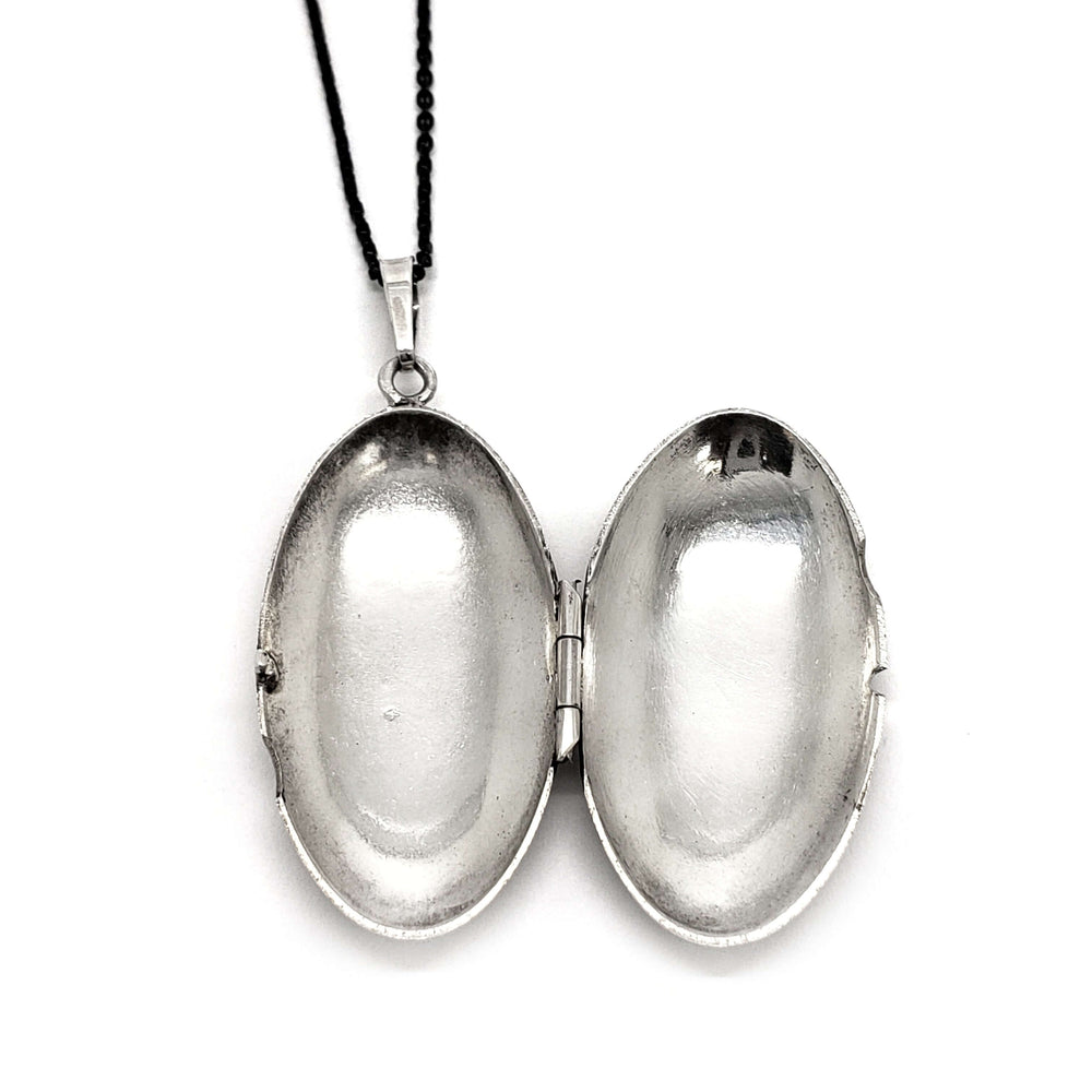 Open vintage sterling silver oval locket showing space for two photos