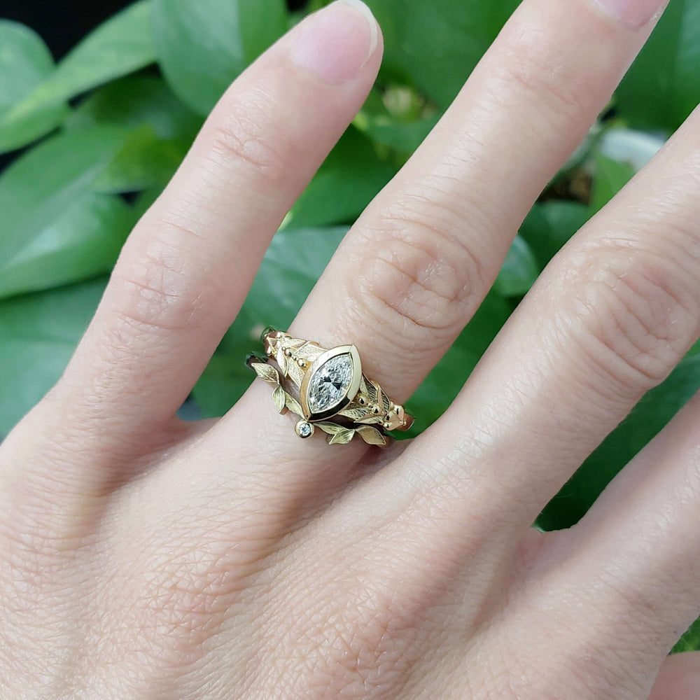 Oriana 14kt yellow gold marquise lab diamond ring stacked with a leaf band on a hand