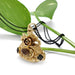 Ornate 18kt yellow gold fob pendant with citrine and peridot, displayed with green leaves