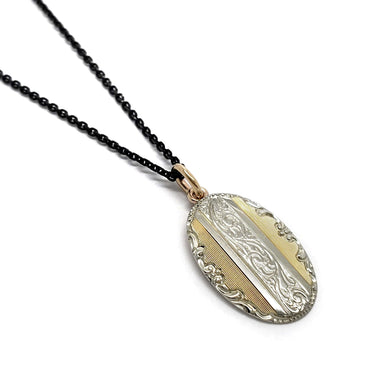 Oval 14kt yellow and white gold pendant with engraved details on a black chain
