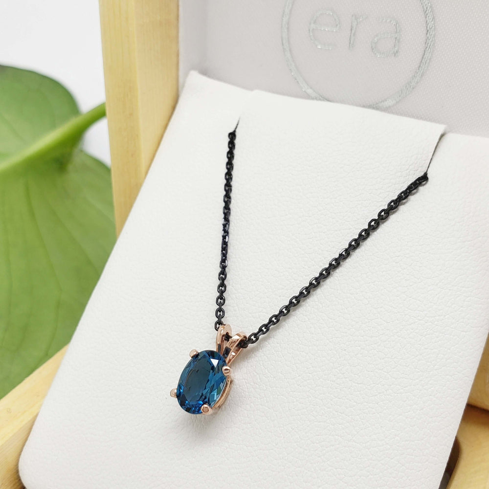 Oval London topaz pendant in 14kt rose gold on a black chain, displayed in a box