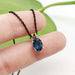 Oval London topaz pendant in 14kt rose gold on a black chain, shown on fingers