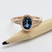 Oval blue Montana sapphire and diamond ring in rose gold, displayed beside a pencil for scale