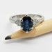 Oval blue sapphire and diamond white gold ring shown beside a pencil for scale