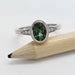 Oval green Australian sapphire and diamond ring in white gold, shown balanced on a pencil