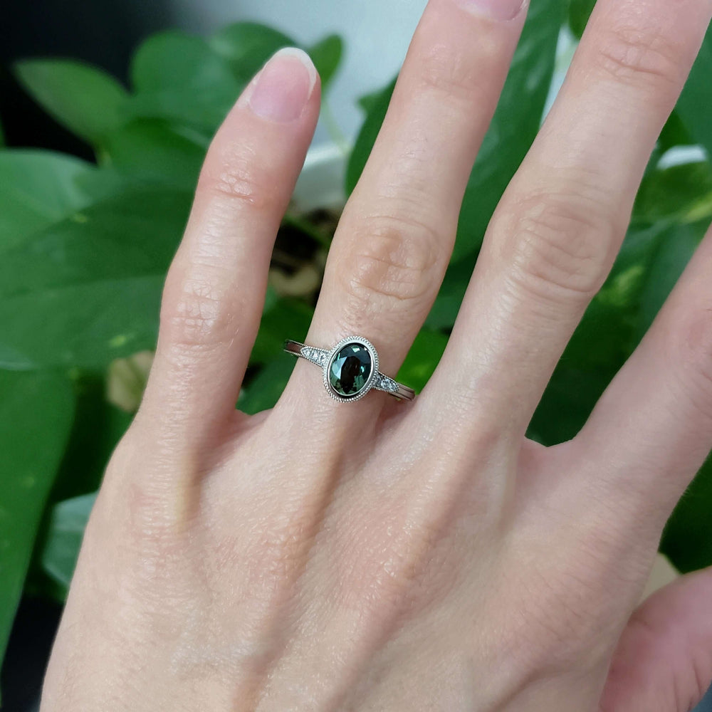 Oval green Australian sapphire and diamond ring in white gold, worn on a hand