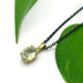 Oval green beryl pendant in yellow gold on a black chain, styled with green leaves