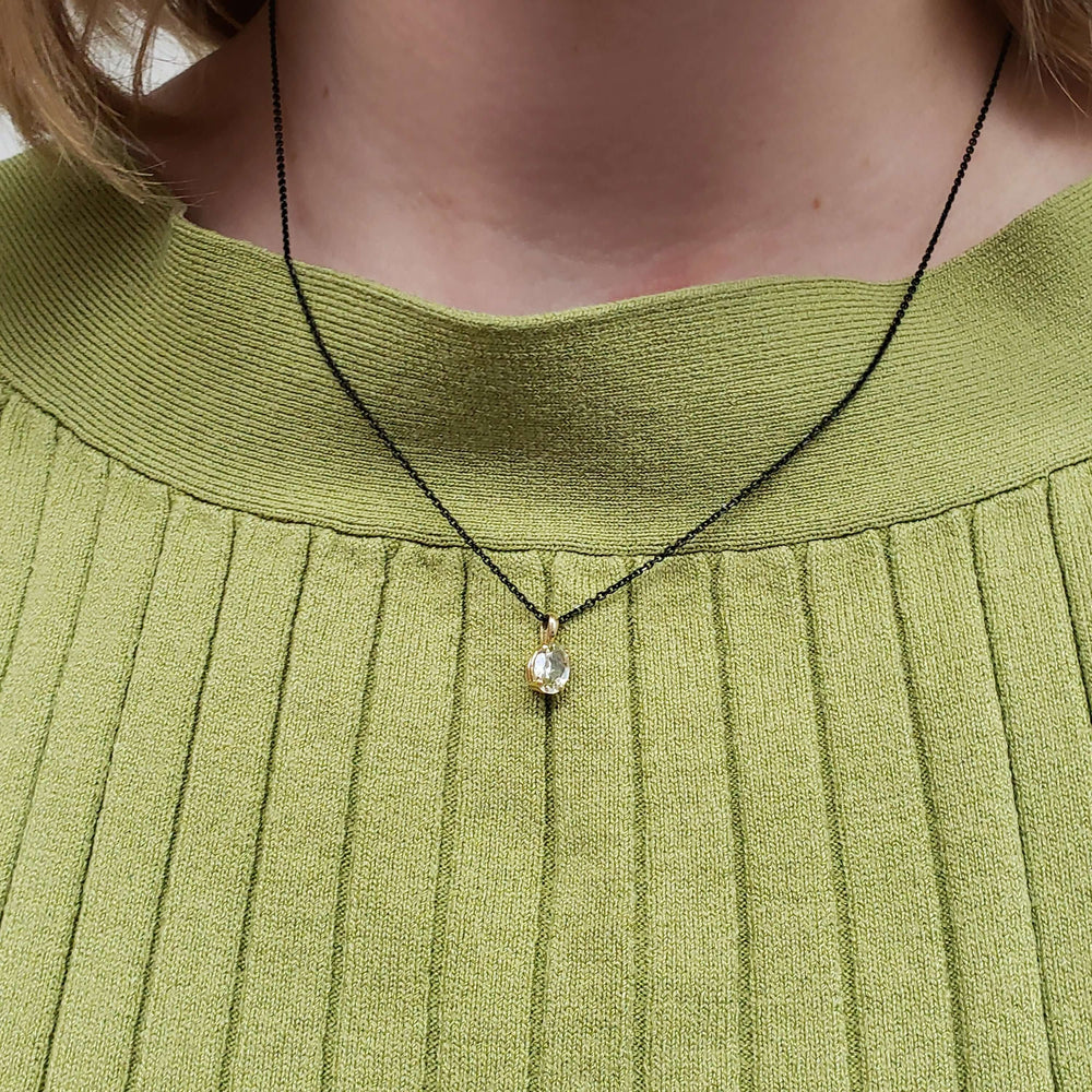 Oval green beryl pendant necklace in yellow gold, worn on a model