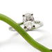 Oval lab-grown diamond solitaire ring in 14kt white gold beside a green stem