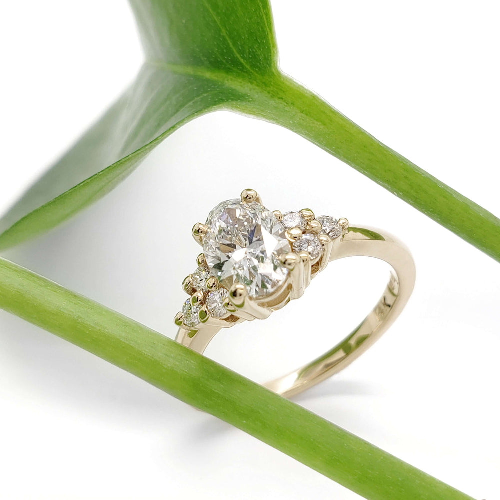 Oval lab diamond engagement ring in yellow gold, styled with green leaf