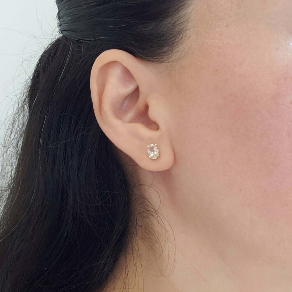 Oval morganite stud earring in 10kt yellow gold shown worn on ear