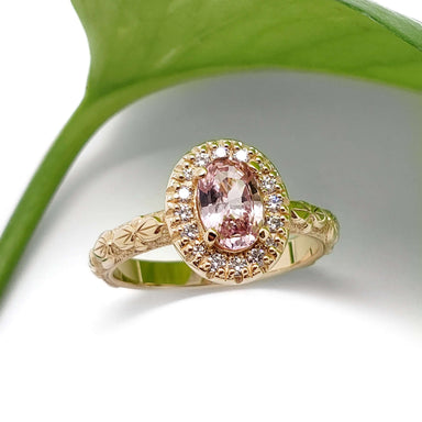Oval peach sapphire and diamond halo engagement ring in 14kt yellow gold, floral engraved band, leaf background