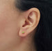 Oval green peridot stud earring in 14kt yellow gold worn on ear