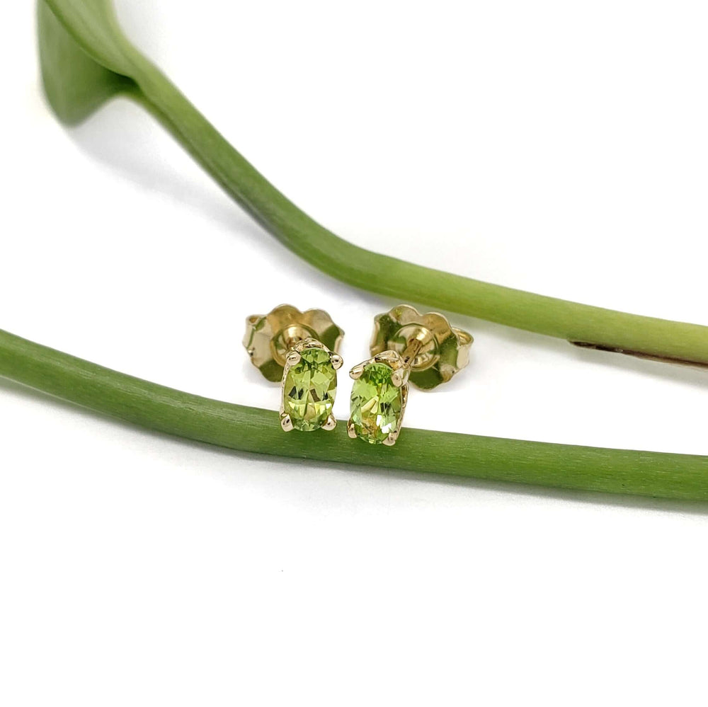Oval green peridot stud earrings in 14kt yellow gold shown with green stems