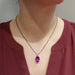 Oval pink sapphire pendant in yellow gold worn on a black chain