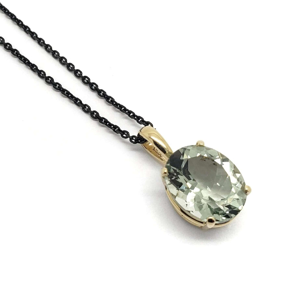 Oval prasiolite pendant in 14kt yellow gold on black chain, close-up on white background