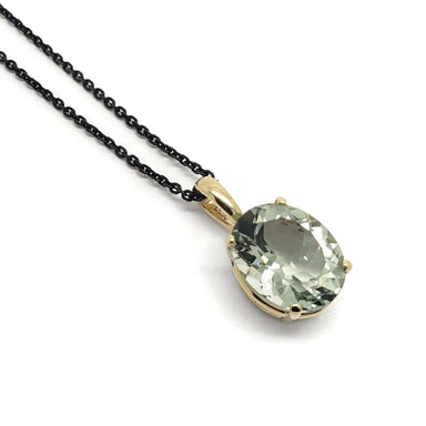Oval prasiolite pendant in 14kt yellow gold on black chain, close-up on white background