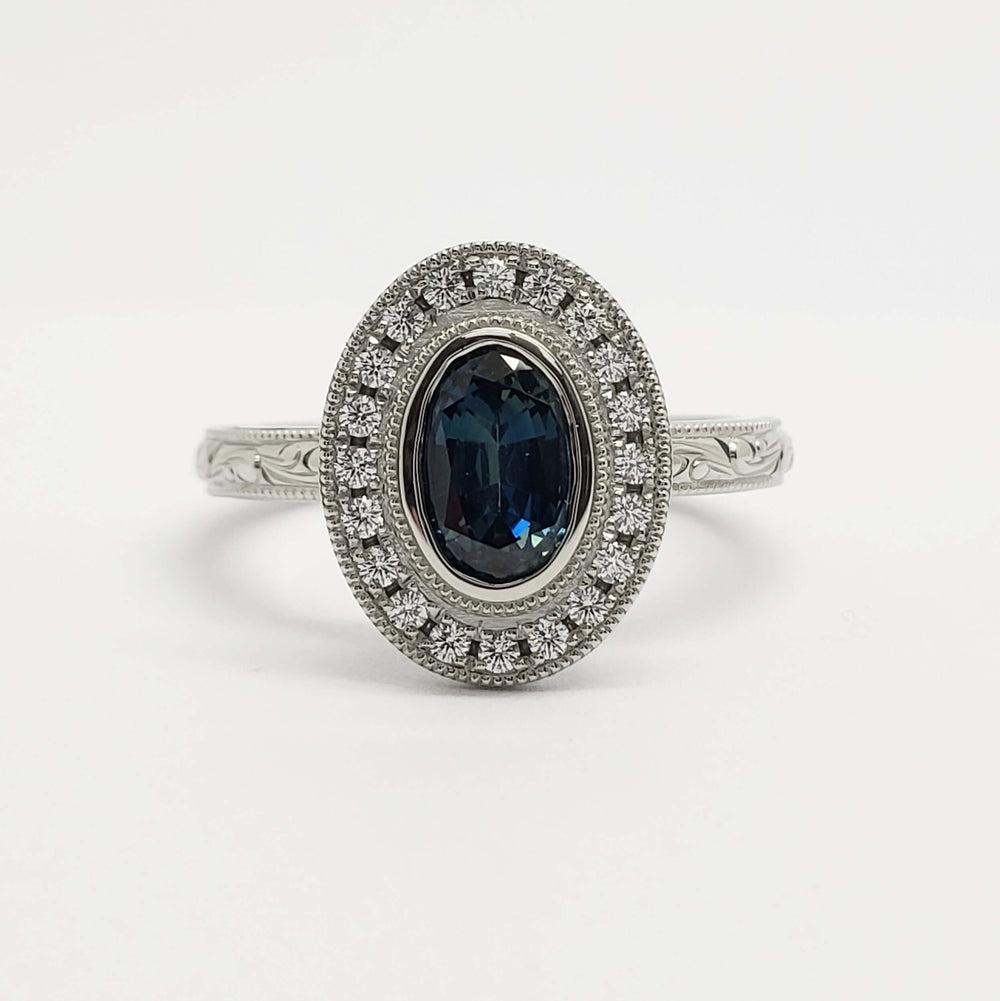 Front view of oval teal sapphire and diamond halo engagement ring in white gold
