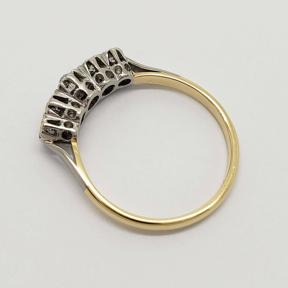 Overhead view of antique five-stone diamond ring showing yellow gold band and platinum gallery
