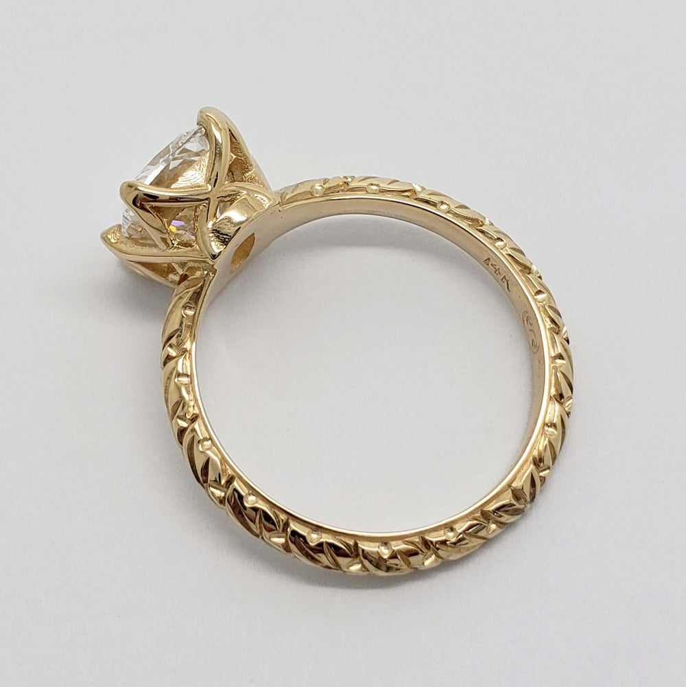 Overhead view of engraved 14kt yellow gold ring with cushion cut lab diamond