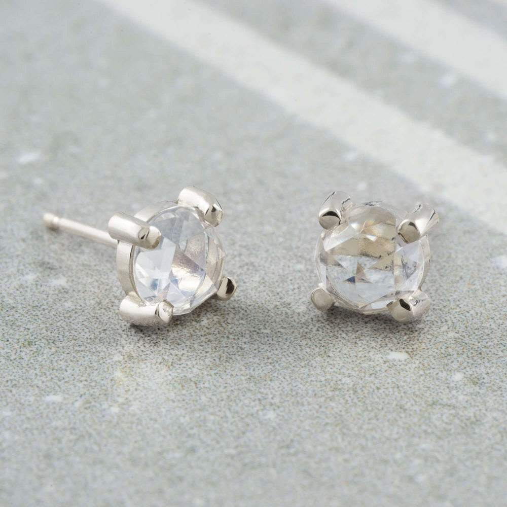 Pair of rose cut moonstone stud earrings in 14kt white gold on stone background