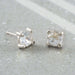 Pair of rose cut moonstone stud earrings in 14kt white gold on stone background