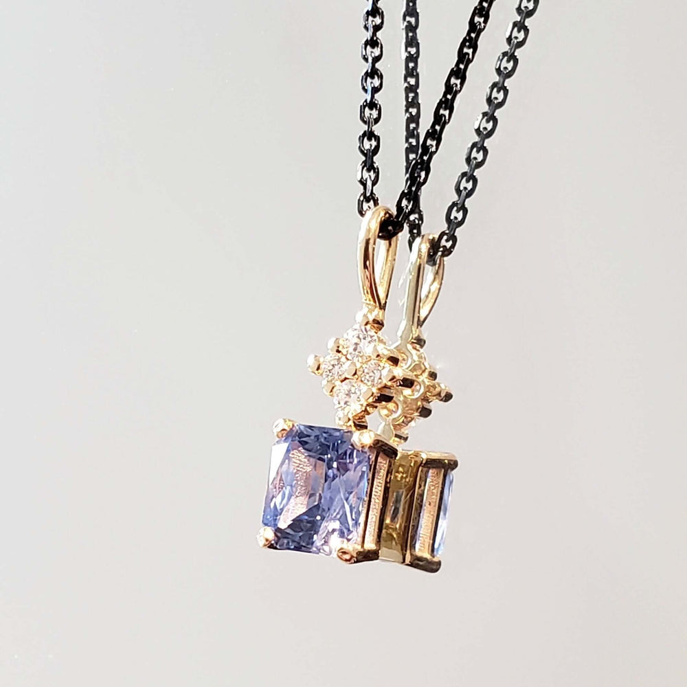Two yellow gold sapphire and lab diamond pendants on black chains, shown together