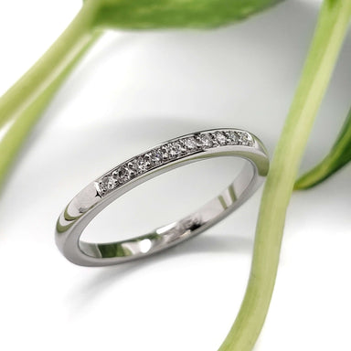 Pave-set lab diamond wedding ring in 14kt white gold beside green leaves