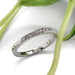 Pave-set lab diamond wedding ring in 14kt white gold beside green leaves