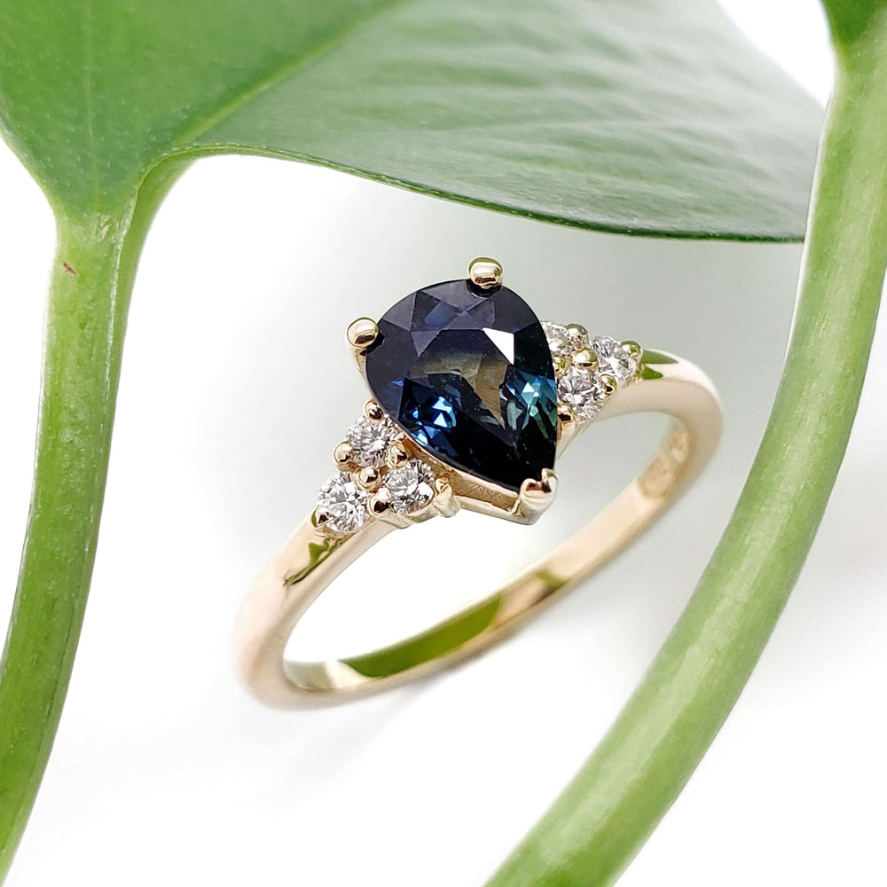 Pear-shaped blue Australian sapphire and diamond ring in yellow gold, with leaf background