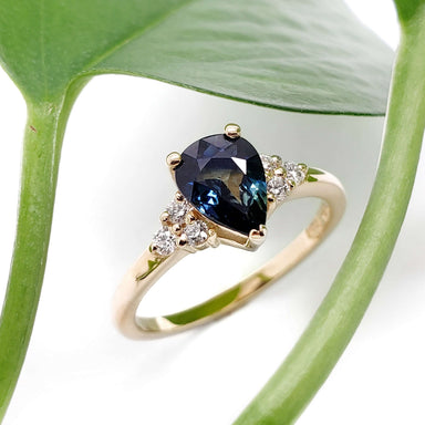 Pear-shaped blue Australian sapphire and diamond ring in yellow gold, with leaf background
