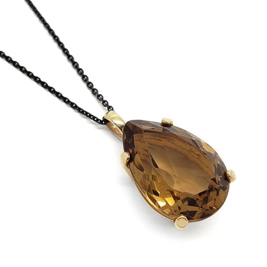 Pear-shaped citrine pendant in 14kt yellow gold on a black chain, angled view