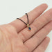 Pear blue sapphire pendant in yellow gold on black chain, shown in hand for scale