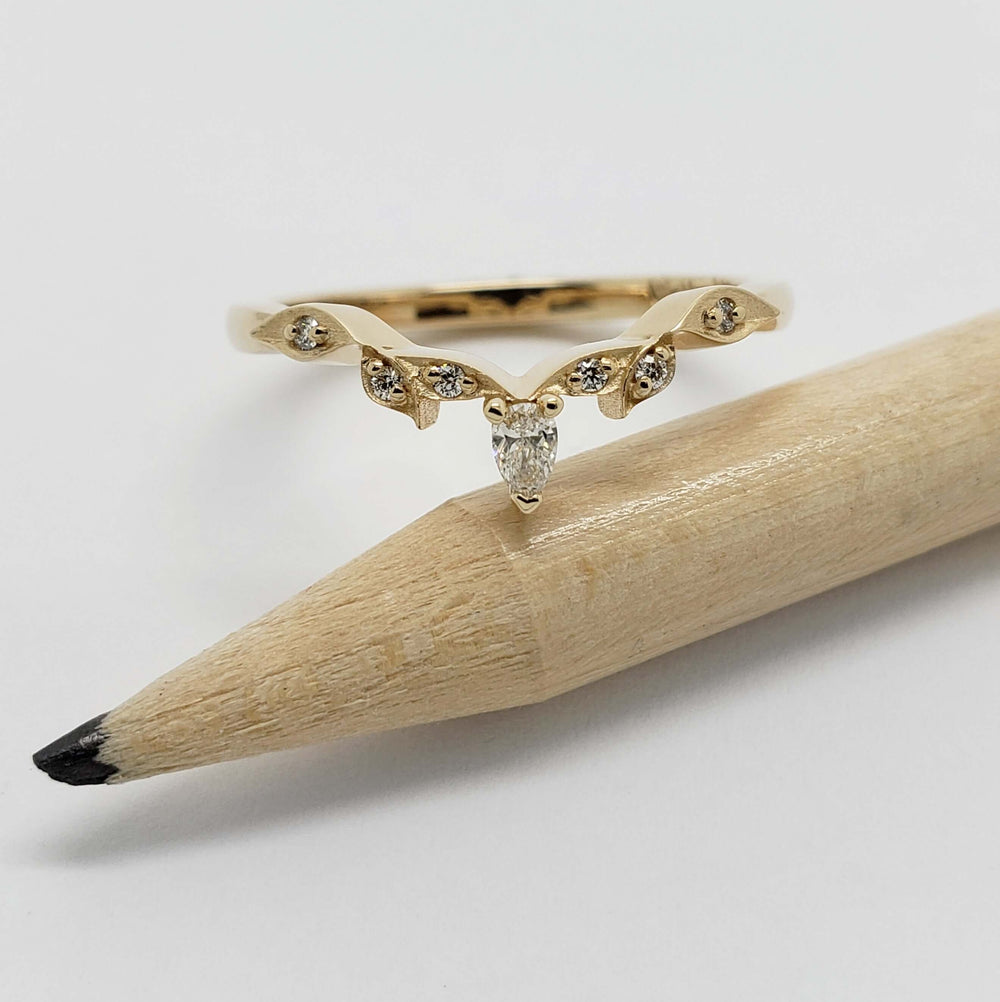 Pear cut diamond leaf wedding ring in 14k yellow gold, displayed on a pencil