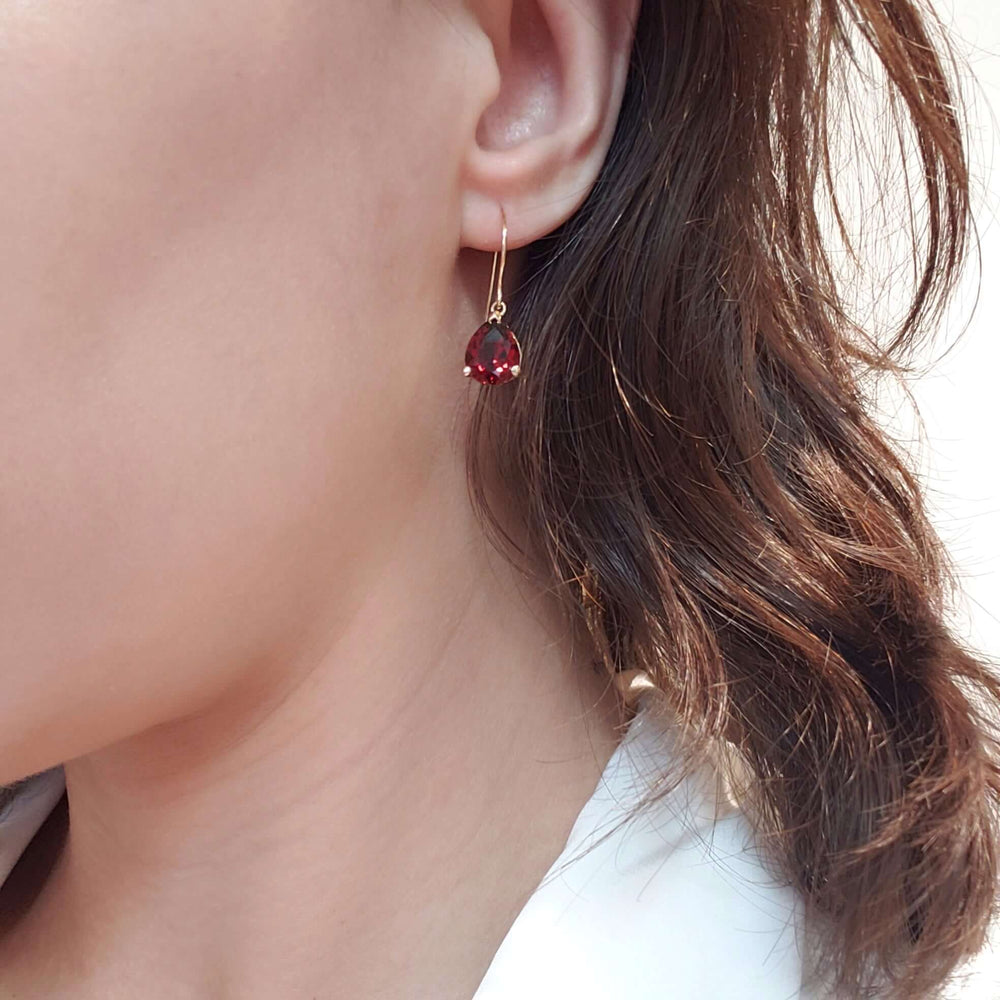 Pear garnet drop earring in 14kt yellow gold worn on ear