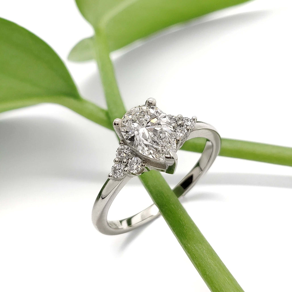Pear lab diamond and accent diamond engagement ring in white gold, styled on green leaf