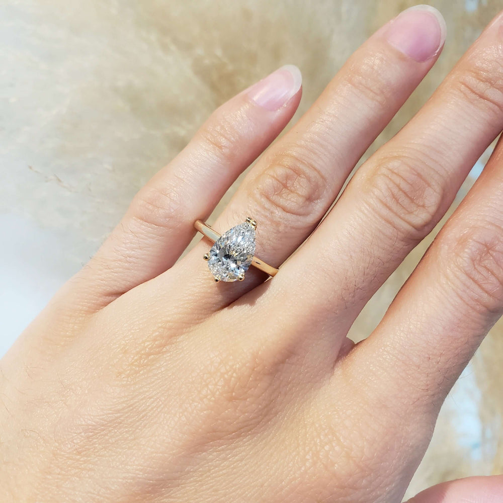 Pear lab diamond engagement ring in yellow gold shown on hand