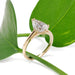 Pear lab diamond engagement ring in yellow gold displayed on green leaf