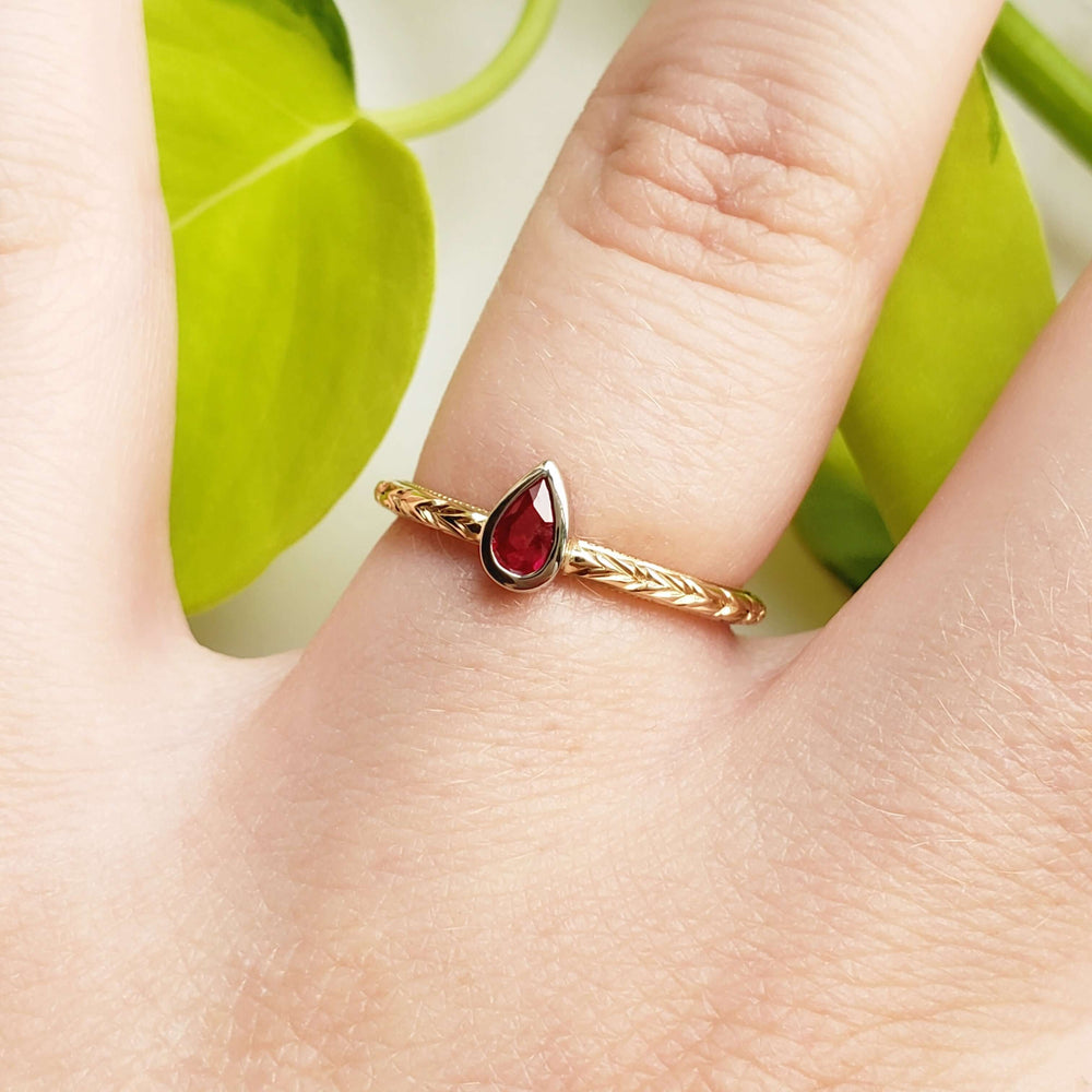 Pear ruby and yellow gold engraved ring worn on hand