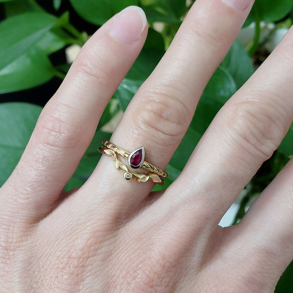 Pear ruby engraved ring stacked with gold leaf and diamond band on hand