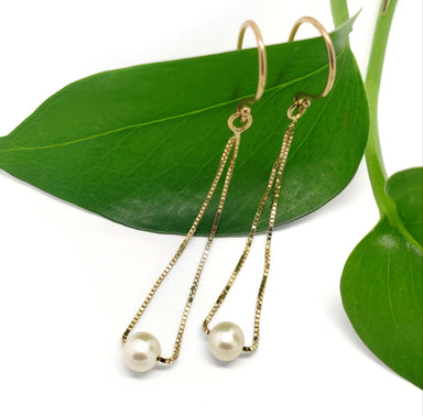 14kt yellow gold teardrop earrings with pearls displayed on a green leaf