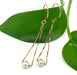 14kt yellow gold teardrop earrings with pearls displayed on a green leaf