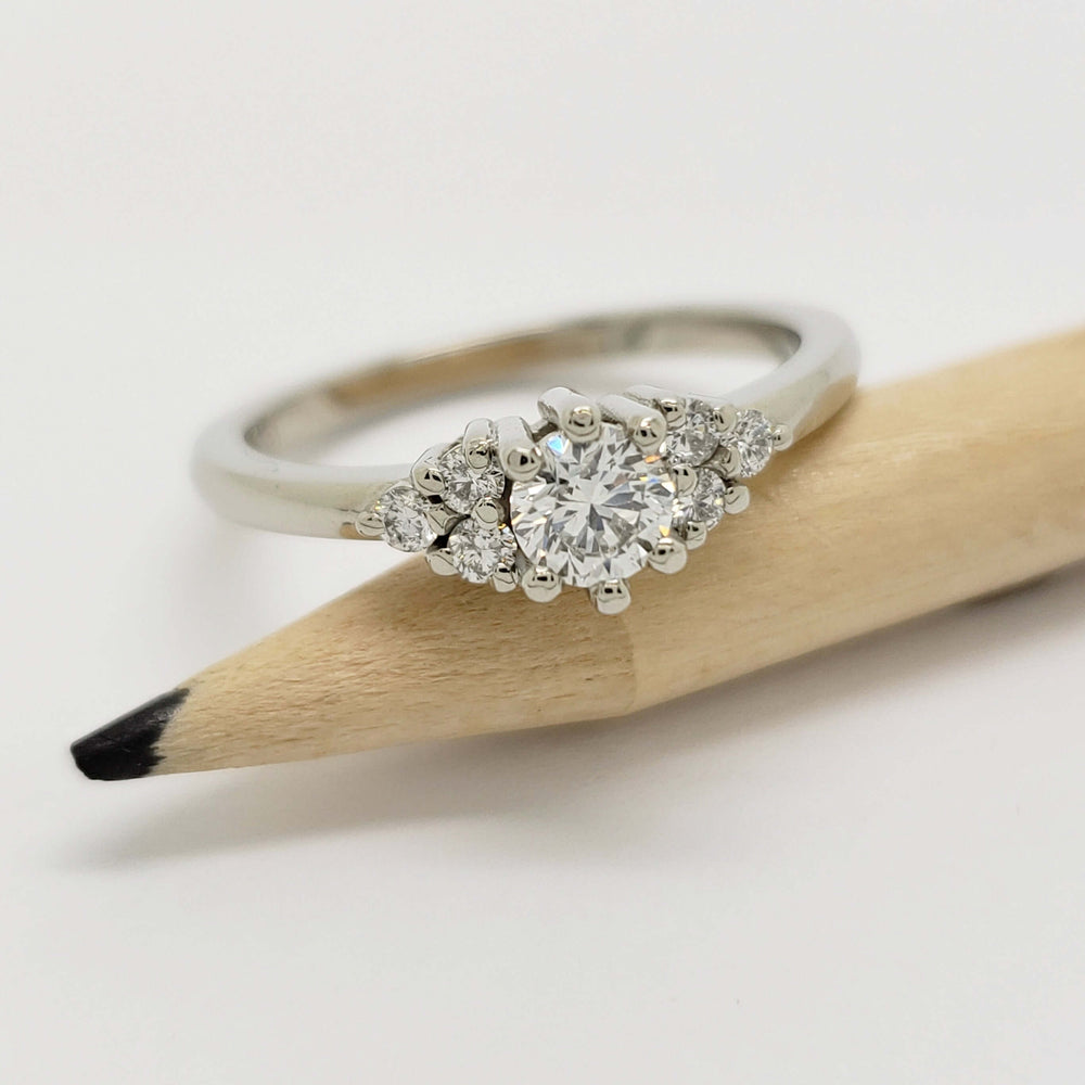 Petite Zira 14kt white gold lab diamond engagement ring resting on a pencil