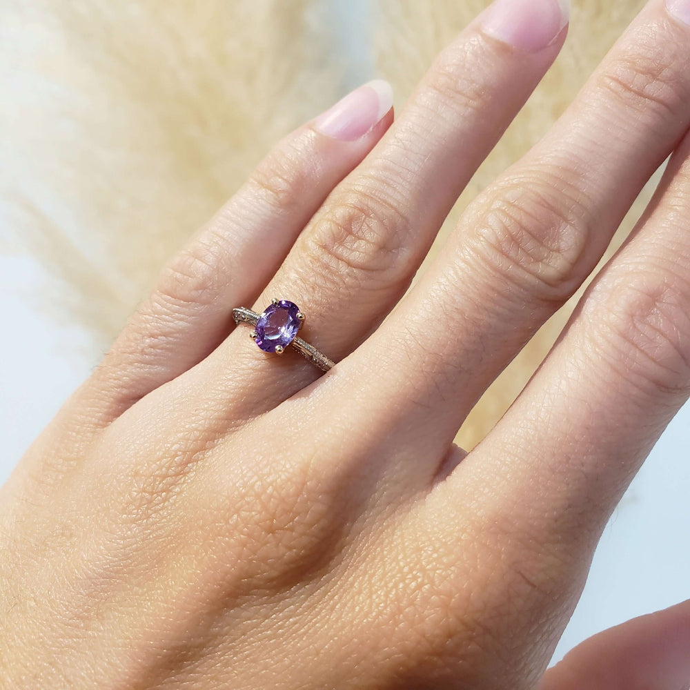 Pink-purple sapphire engagement ring in white and yellow gold shown on hand
