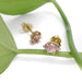 Pink imperial topaz and 14kt yellow gold stud earrings resting on a green leaf